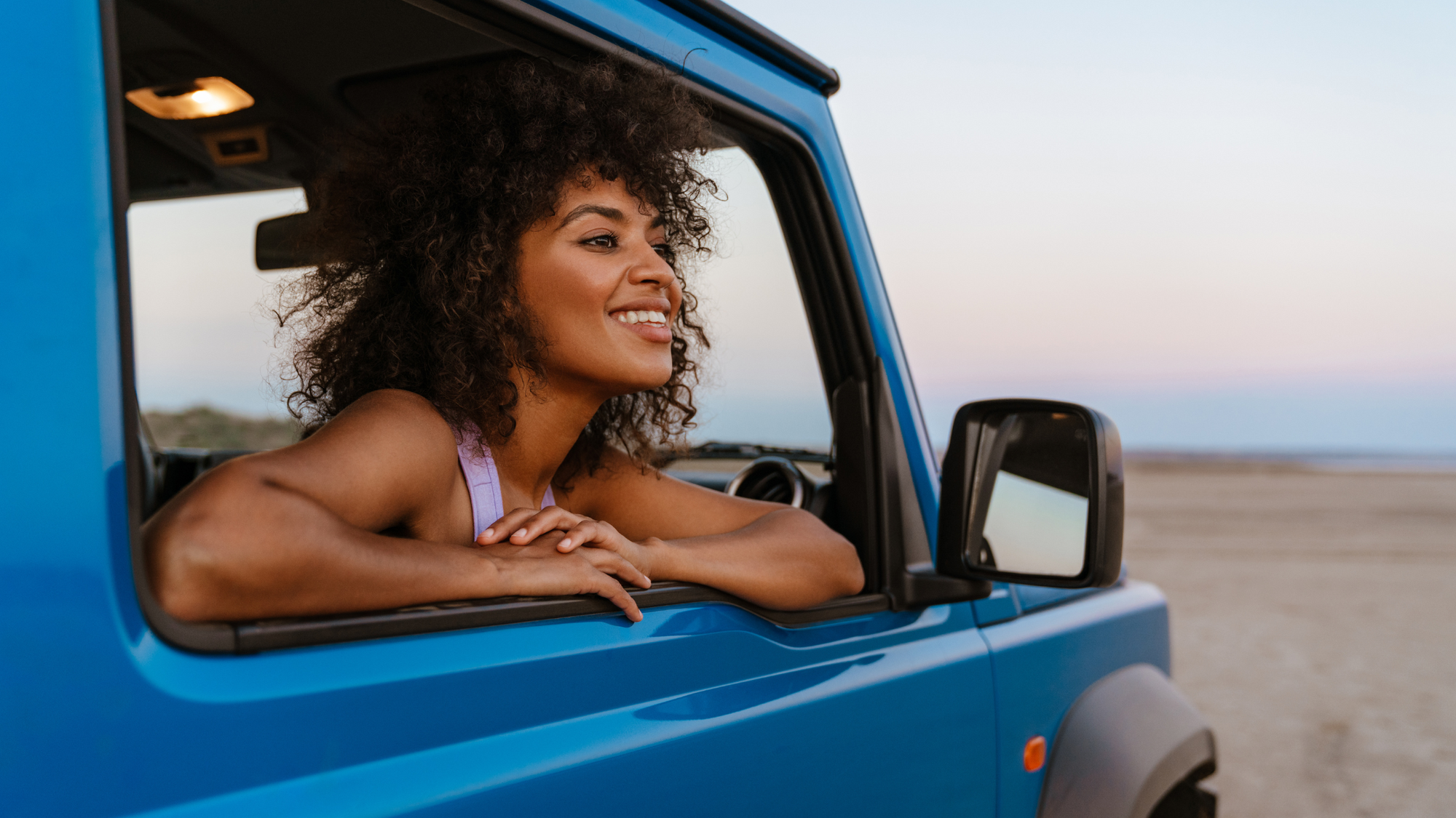 woman in blue car on the beach